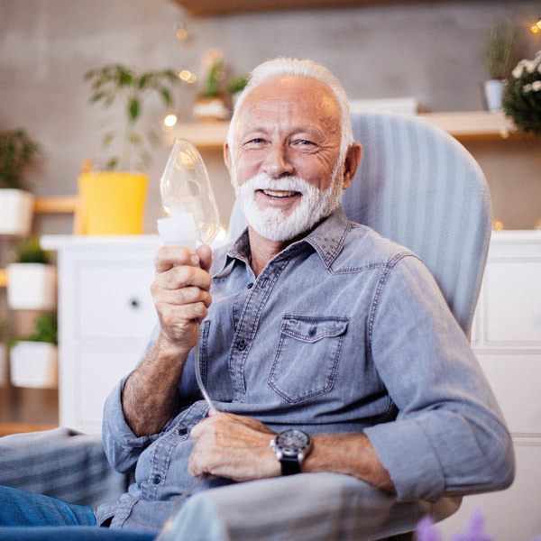 man with breathing machine sitting in a chair