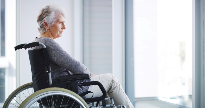 An elderly woman sitting in a wheelchair is looking out the window in Houston, TX