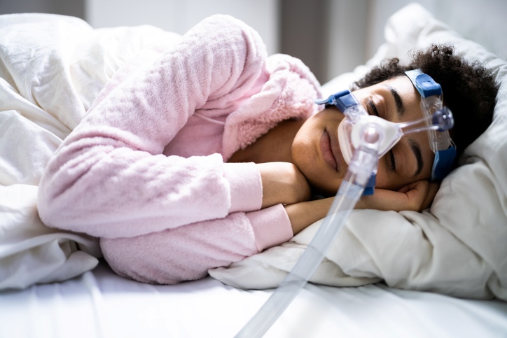 A Person sleeping in bed wearing a CPAP mask for sleep apnea in Houston, TX